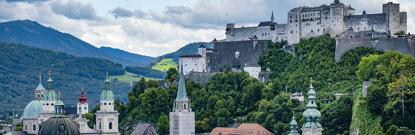 Blick über die Salzburger Altstadt zur Festung Hohensalzburg und zu den umliegenden Hügeln